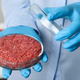 hands holding ground beef in petri dish